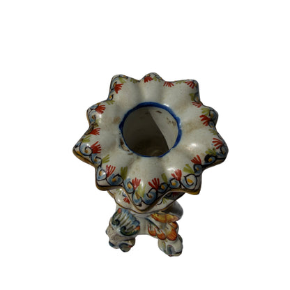 Side view of glazed ceramic candlestick with scrolling feet and polychrome paint