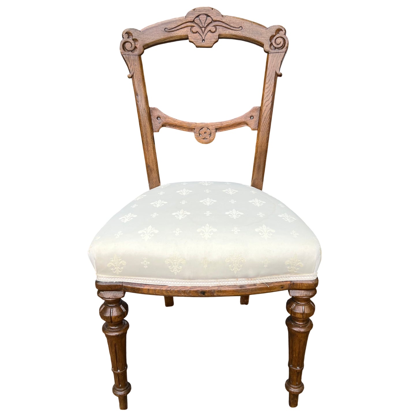 Front view of Victorian carved oak dining chair with padded cream seat