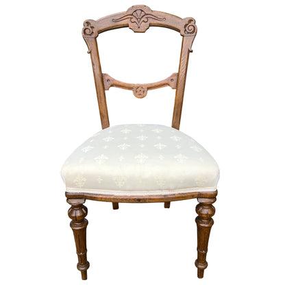 Front view of Victorian carved oak dining chair with padded cream seat