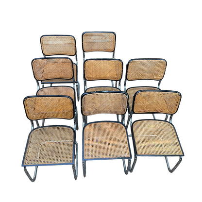 Front view of eight vintage Arrben cane dining chairs arranged in rows showing woven seats and backs
