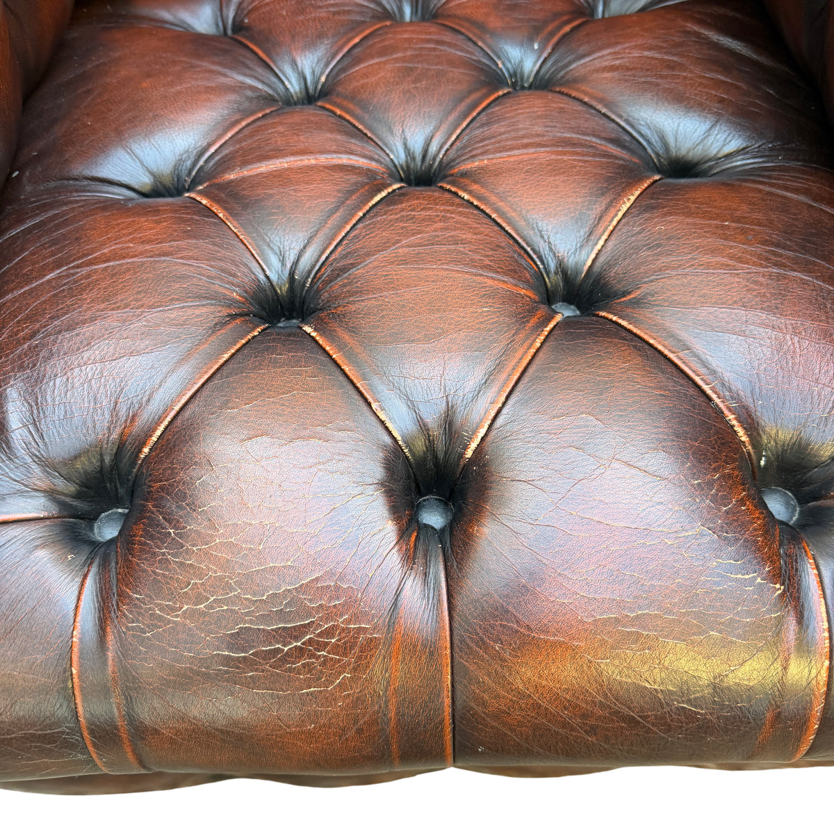 Detail of worn leather folds and creases on the armrest of a Chesterfield chair