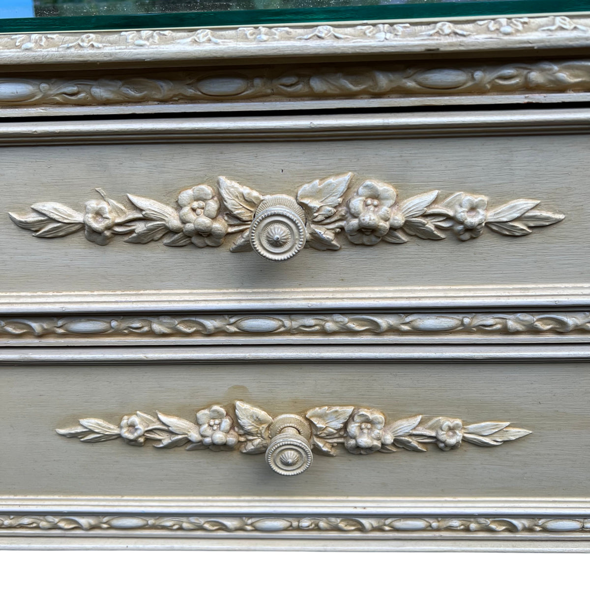 Side view of small vintage chest of drawers with painted finish and applied decoration
