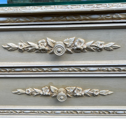 Side view of small vintage chest of drawers with painted finish and applied decoration