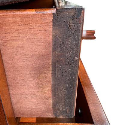 Three-quarter view of vintage mahogany tall chest of drawers in outdoor setting