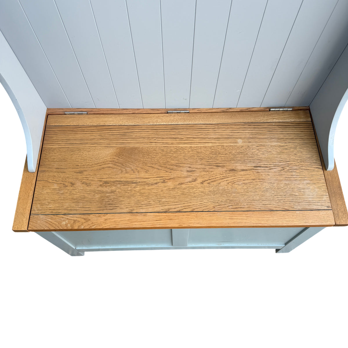 Close view of hinged oak seat top revealing internal storage on painted bench