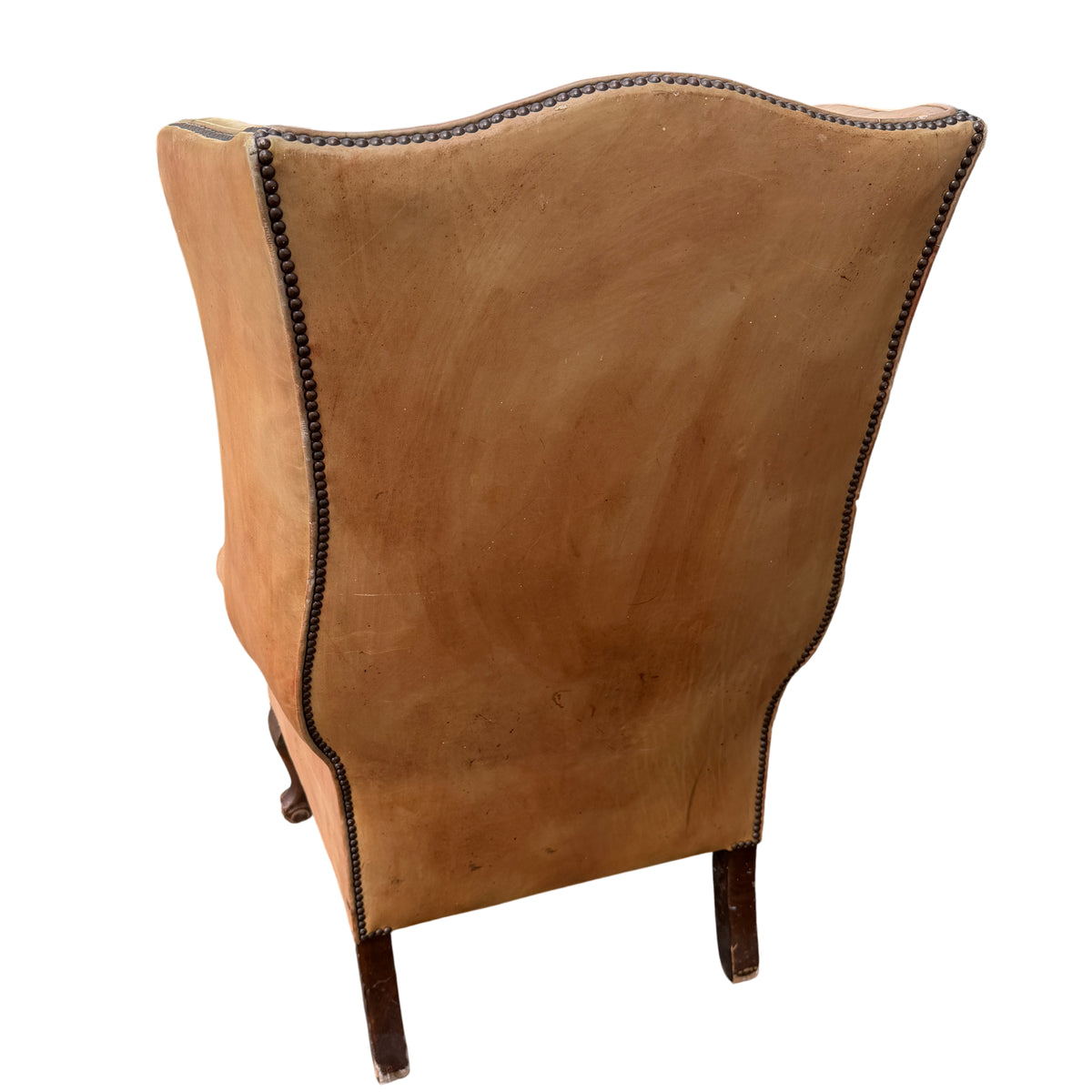 Lower apron and studs of a vintage leather armchair with worn leather seat