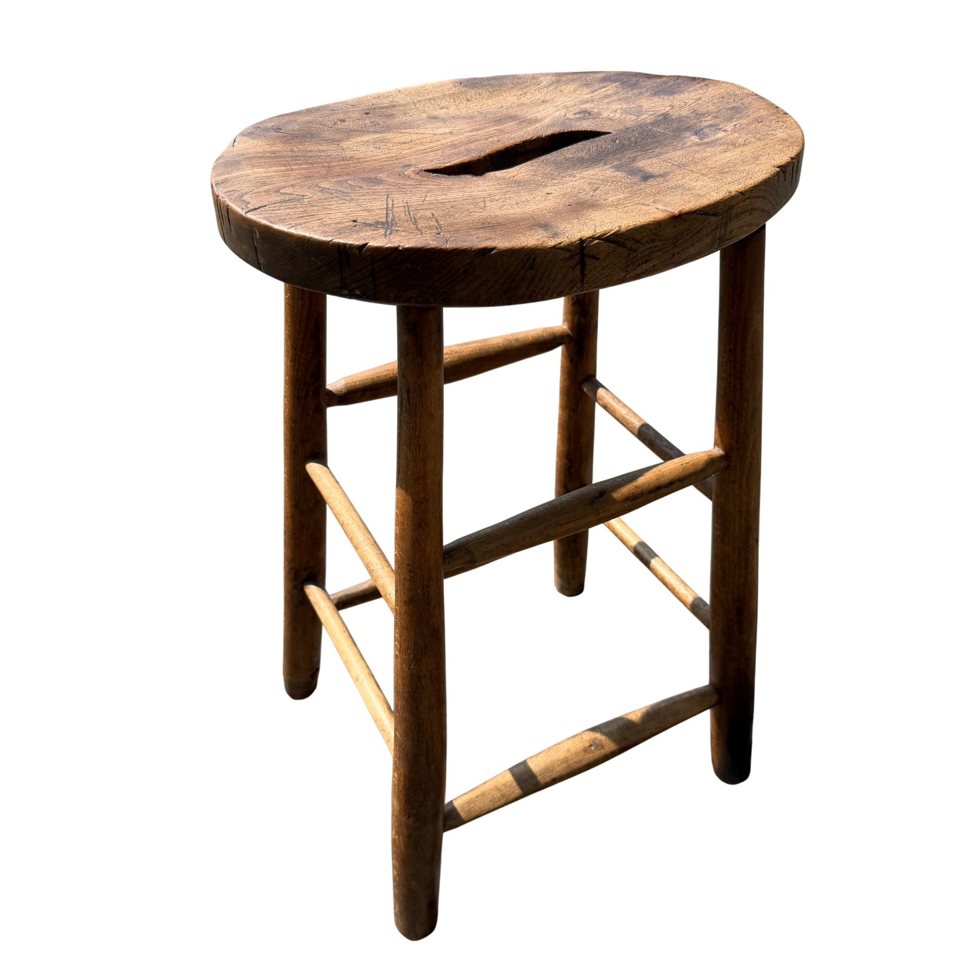 Full view of vintage wooden stool on pavement showing four legs and stretchers