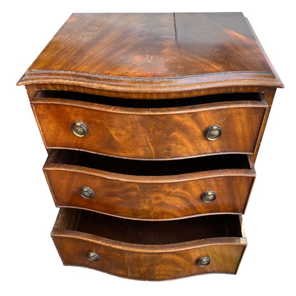 Serpentine-front drawers on small mahogany bedside chest