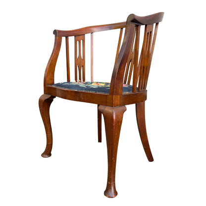 Curved top rail and vertical slats on Arts & Crafts wooden armchair with needlepoint seat