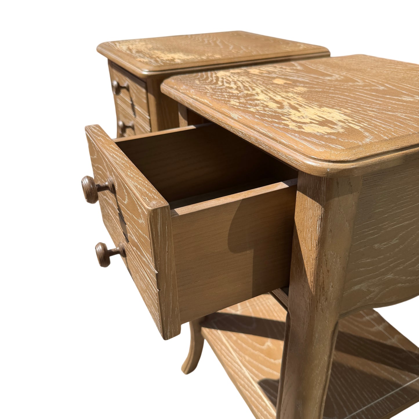 Pair of small bedside cabinets displayed outdoors on concrete surface