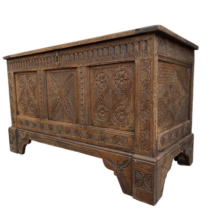 Carved oak coffer chest with Jacobean-style carved panels and brass escutcheon