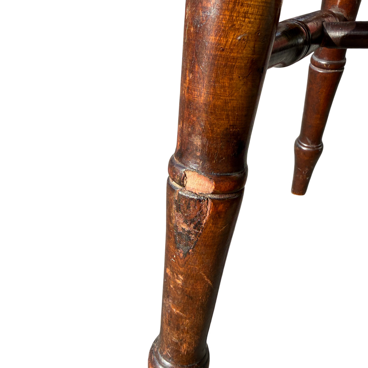 Top of spindle back on a vintage penny-seat chair with scuffed stain and scratches