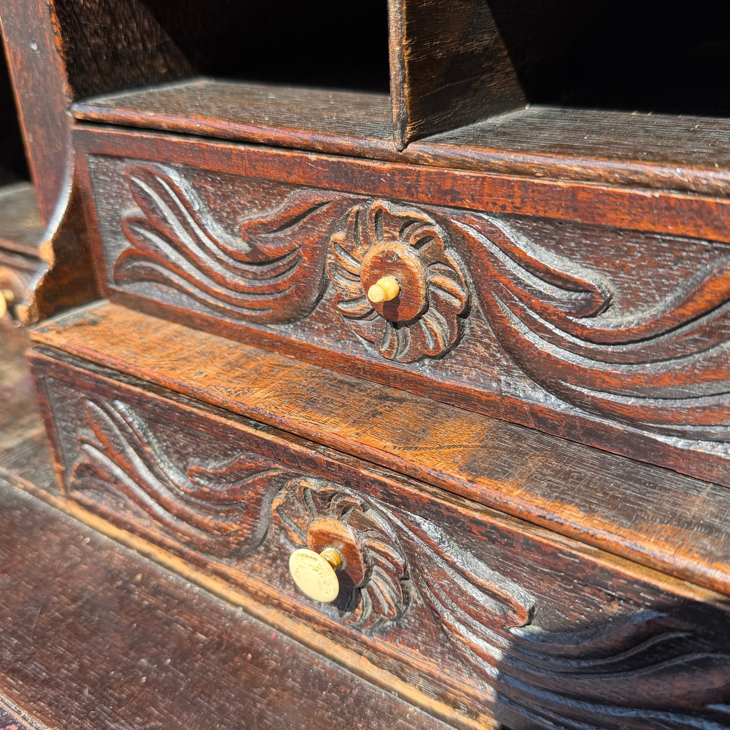 Detail of carved face motif on upper doors of oak bureau bookcase