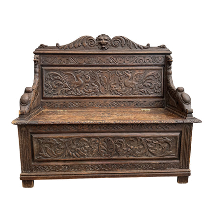 Detail of lion-mask cresting and carved acanthus on oak storage bench