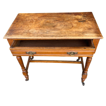 Side view of pine table with turned legs and cross stretcher base on castors