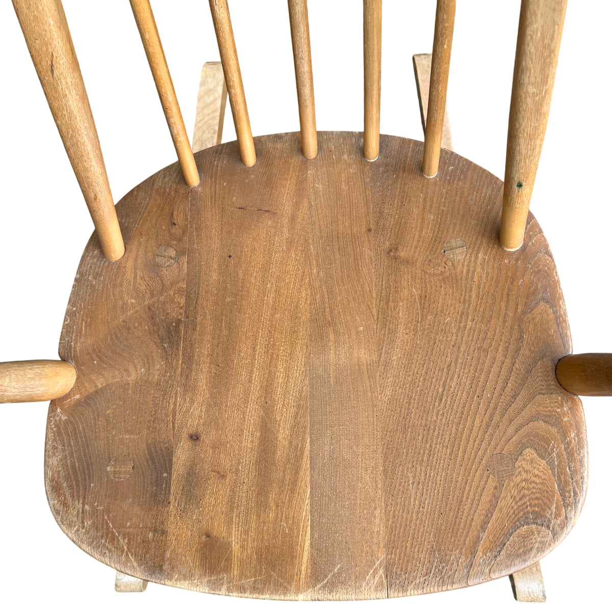 Wooden rocking chair seat with visible surface wear and scratches on light wood finish