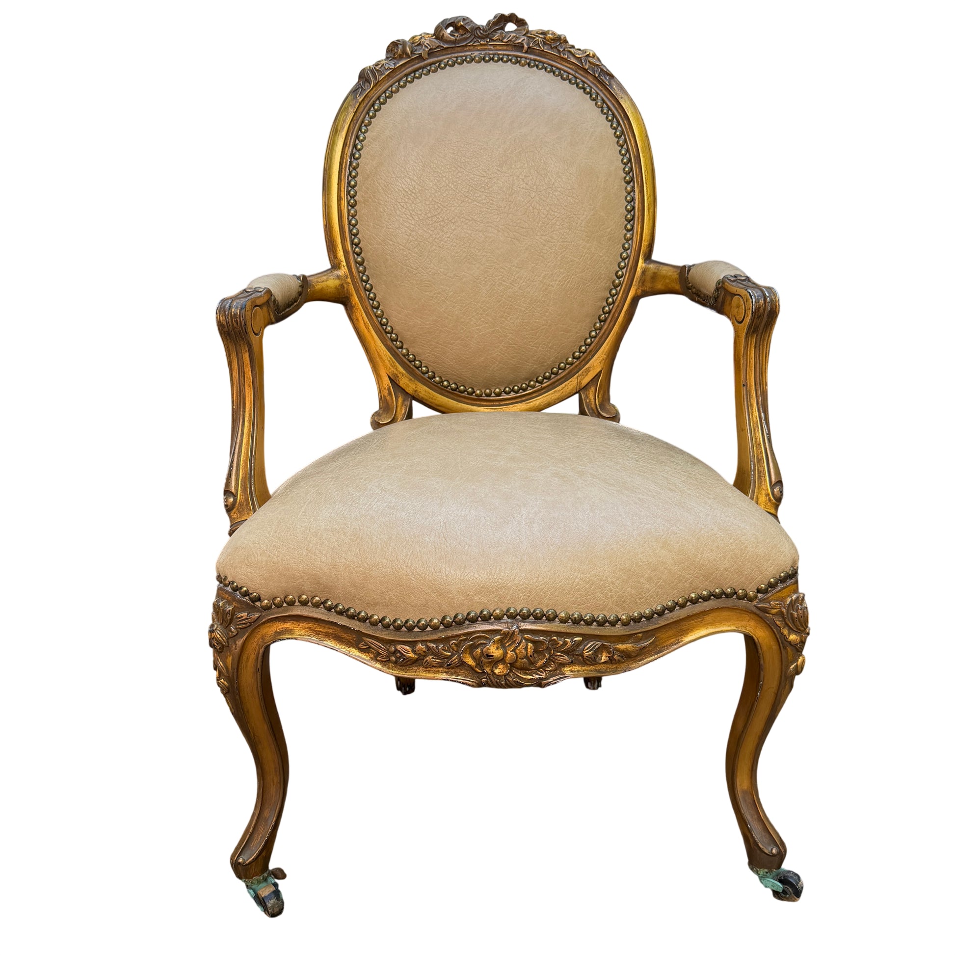 Gilt Louis-style armchair with carved wooden frame and beige faux leather upholstery, oval back and brass studs