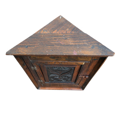 Full front view of small oak wall mounted corner cabinet with carved door