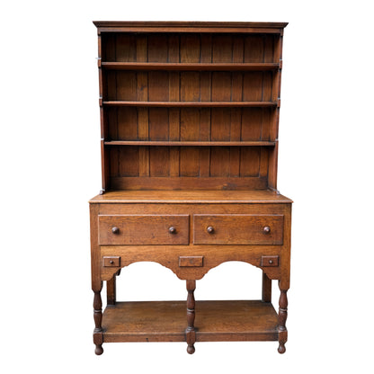 Front view of oak Welsh dresser with panelled back and multiple open shelves