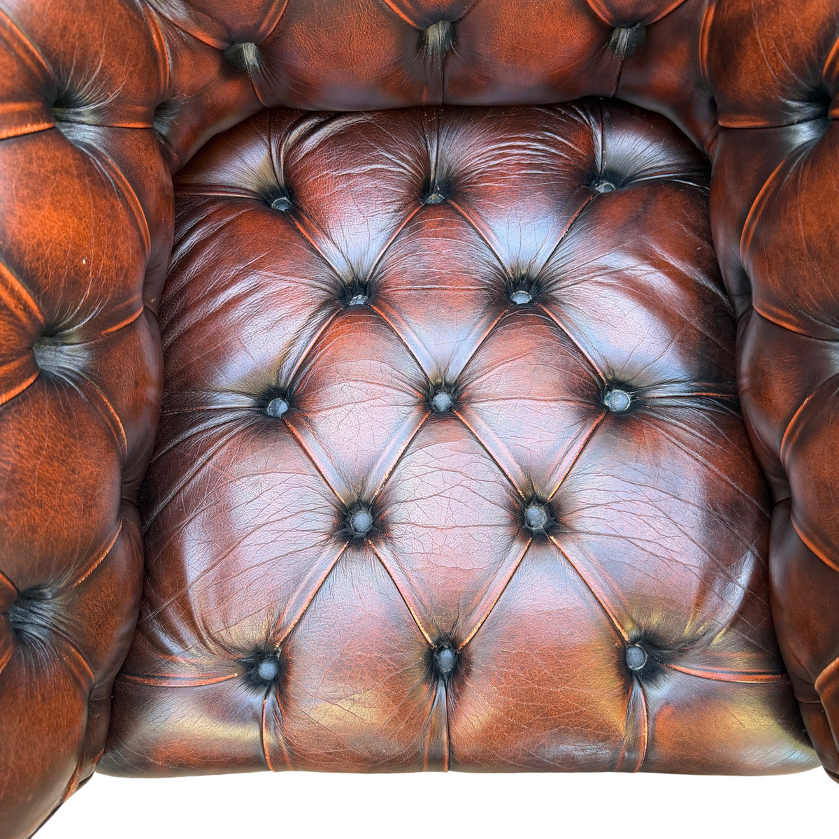 Front view of brown leather Chesterfield armchair showing seat cushion and tufting
