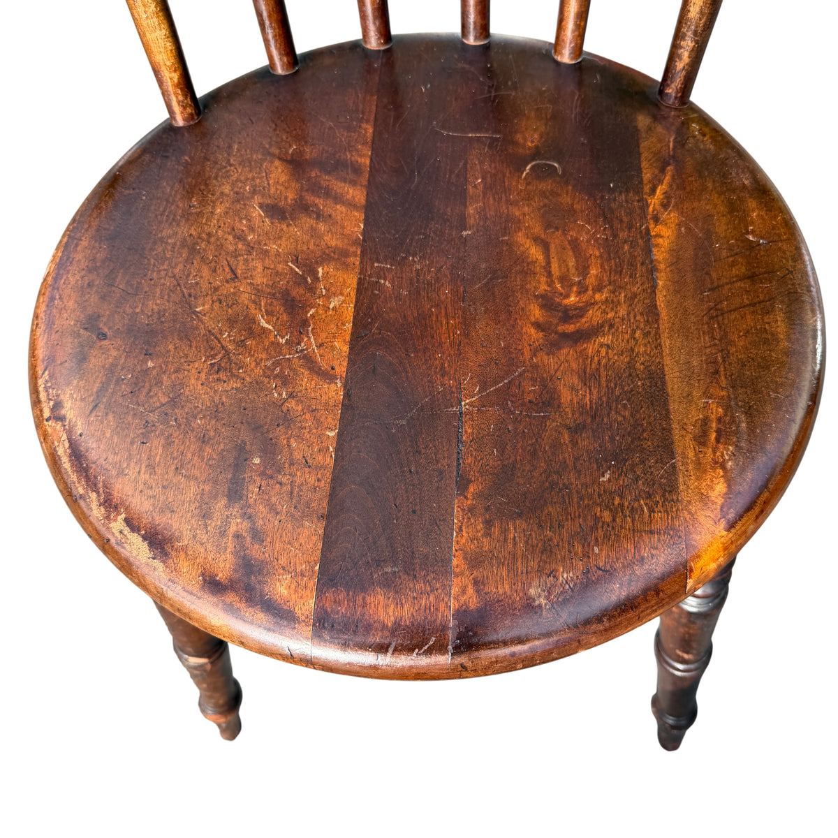 Front view of vintage wooden dining chair with round penny seat and spindle back