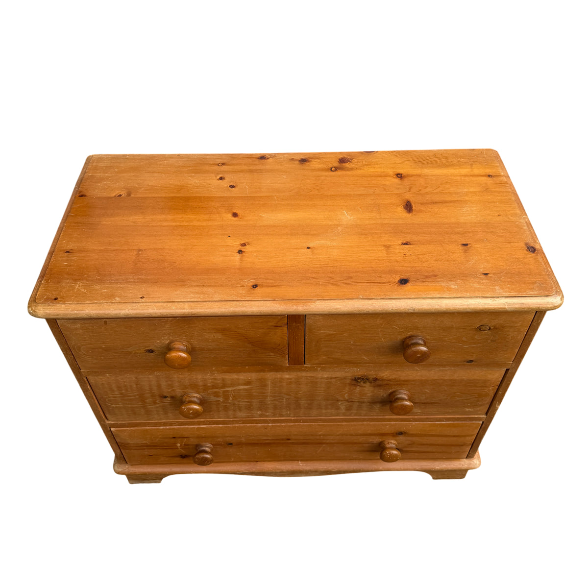 Pine bedroom chest featuring turned wooden knob handles and shaped plinth base