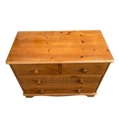 Pine bedroom chest featuring turned wooden knob handles and shaped plinth base