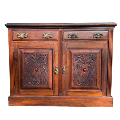 Close up of carved foliate panel on a Victorian wooden sideboard cupboard