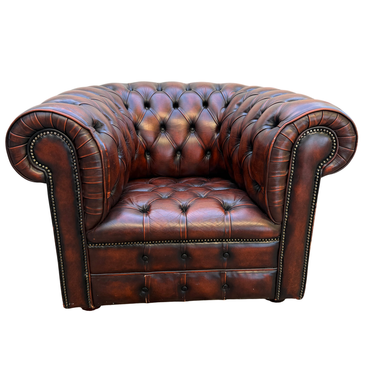 Brown leather Chesterfield armchair showing studded rolled arm and button tufting