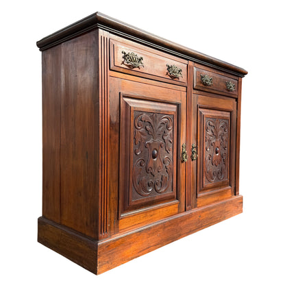 Pair of ornate brass drawer handles on a carved wooden sideboard