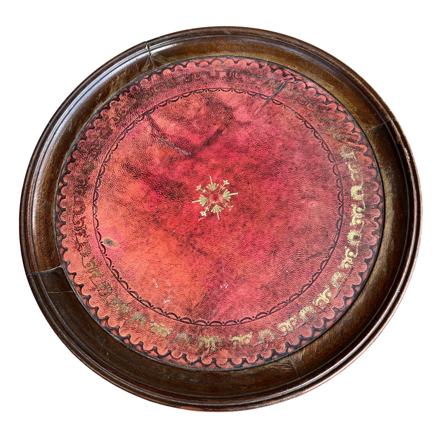 Top view of round red tooled leather inset showing decorative tooling on mahogany table