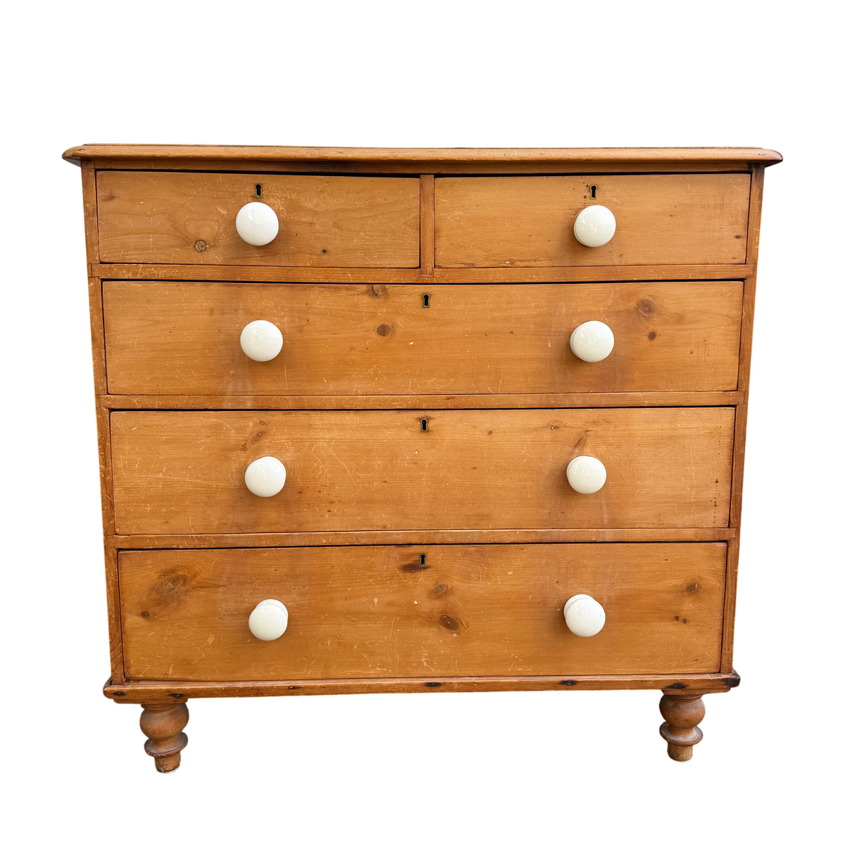Front view of Victorian pine chest of drawers with white ceramic knobs and key escutcheons