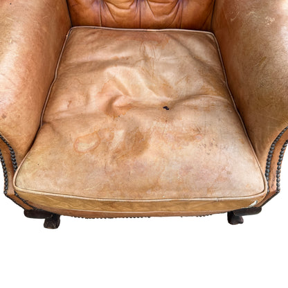 Close view of the deep button back and tufted leather on a vintage wingback armchair