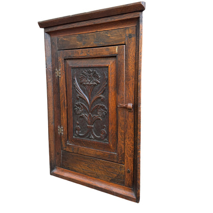 Arts & Crafts oak corner wall cabinet with carved floral panel and original latch