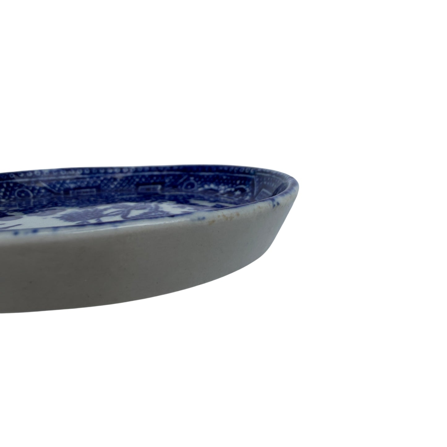 Rim detail of blue and white ceramic butter pat with patterned border