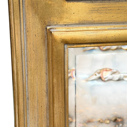 Close-up of gilt finish showing fine speckling and surface texture on mirror frame