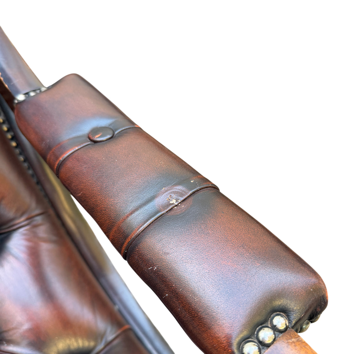 Close-up of padded leather armrest with studded trim on vintage armchair