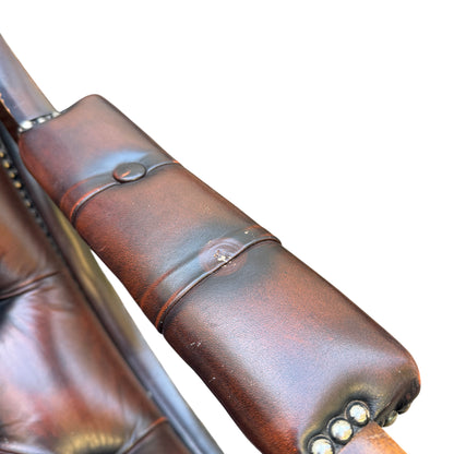 Close-up of padded leather armrest with studded trim on vintage armchair