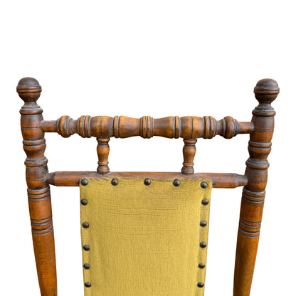 Front view of child-sized rocking chair with turned spindles and upholstered seat