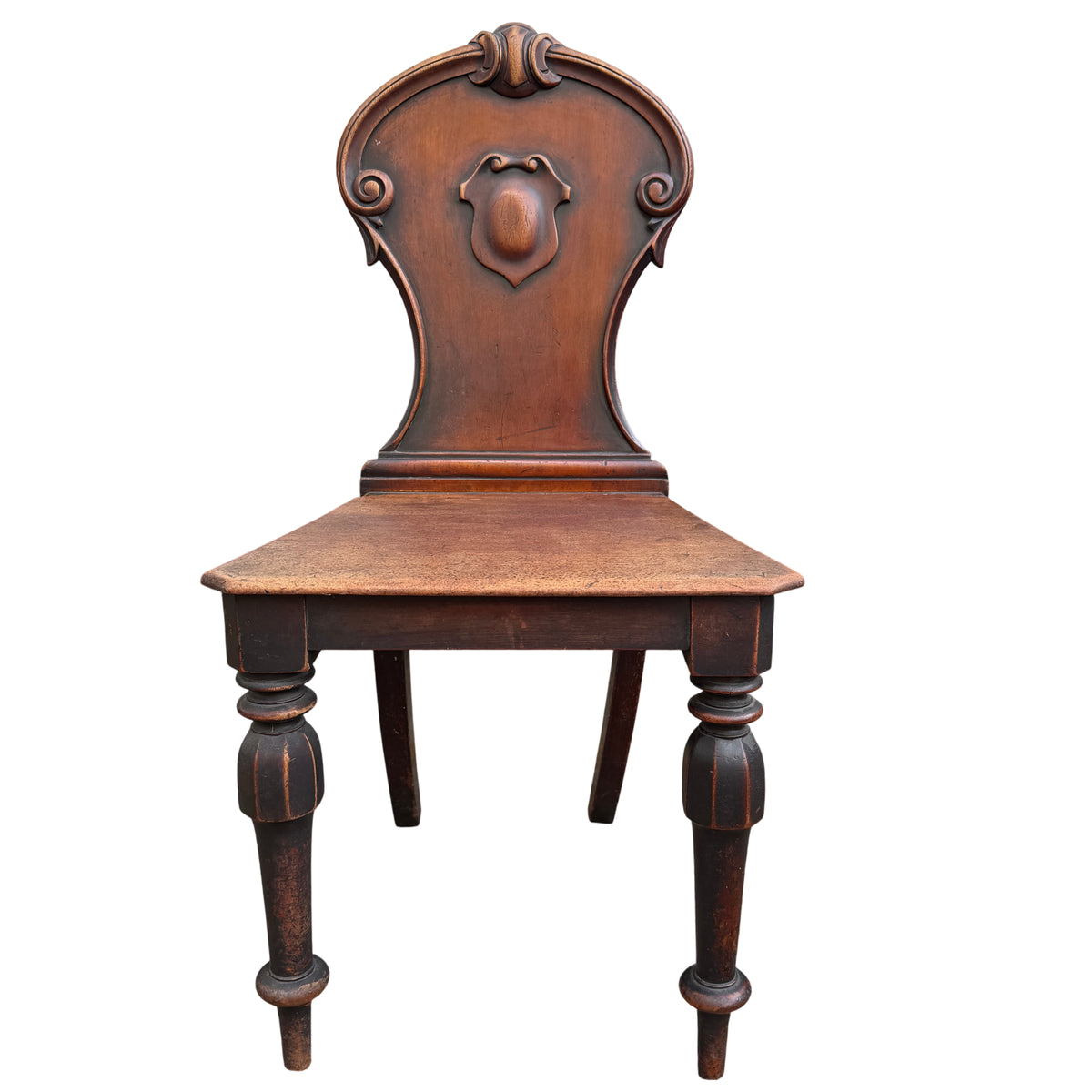 Carved shield-shaped back of mahogany hall chair with scroll detailing