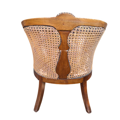 Three-quarter view of carved wooden armchair with cane back and sides