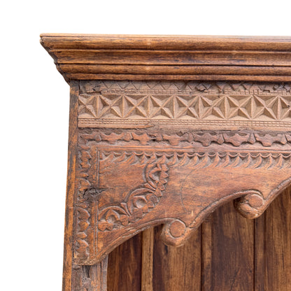 Front view of tall carved oak bookcase with three interior shelves